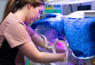 A nurse cares for a newborn in an incubator