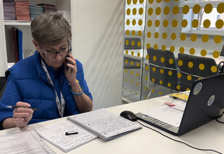 A woman in the uniform of an employee of the Survivor relief Centre in Odesa communicates with clients on the phone