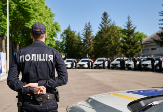 Policeman standing in front of 13 police cars during the handover ceremony