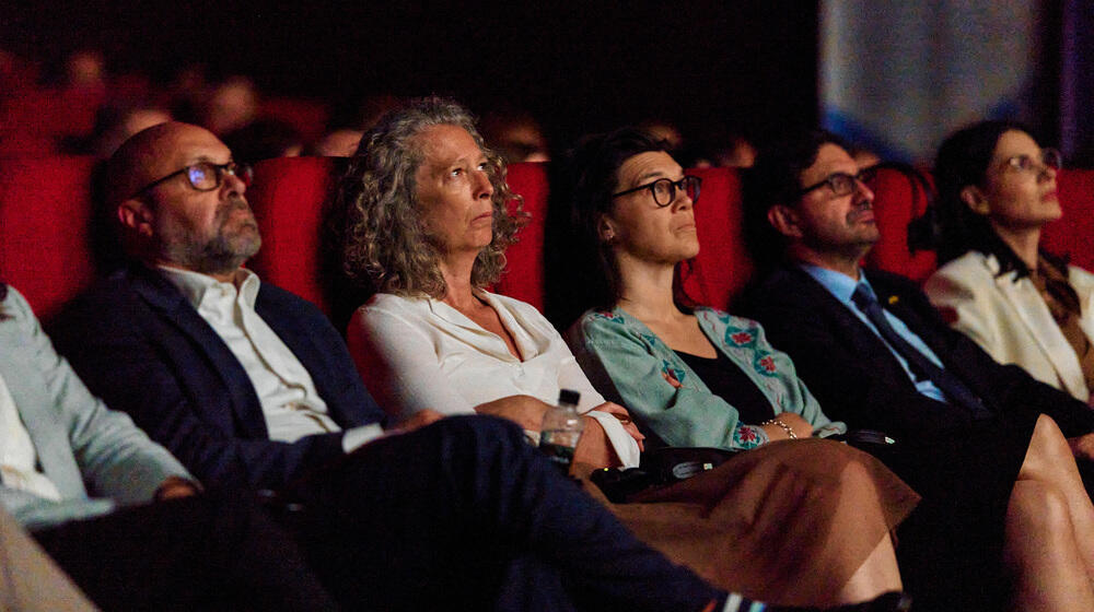 The audience watches the documentary "Behind the Silence"