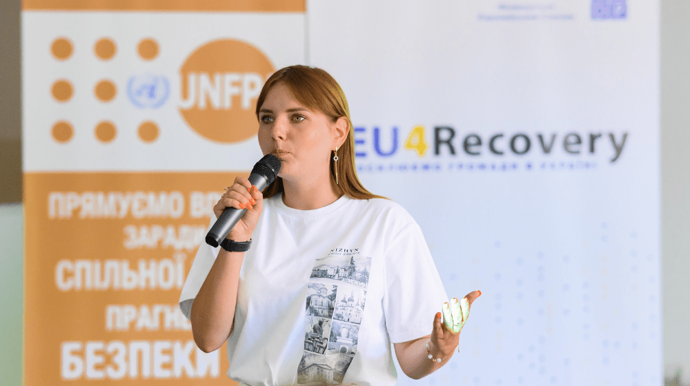 A young woman with UNFPA and EU4Recovery banners