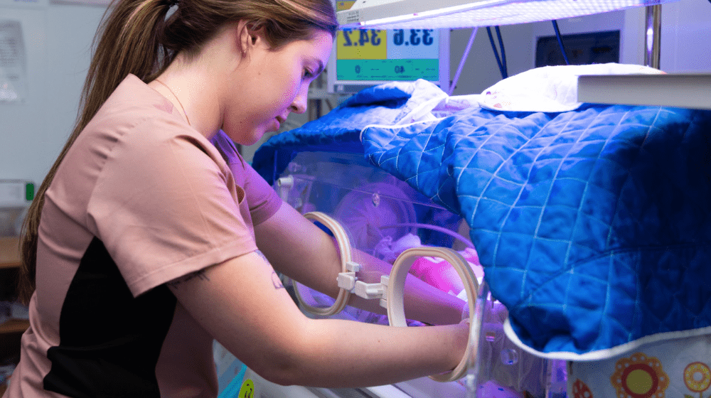 A nurse cares for a newborn in an incubator