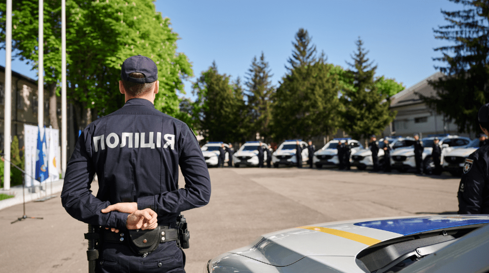 Police officers stand in front of the transferred cars during the official ceremony